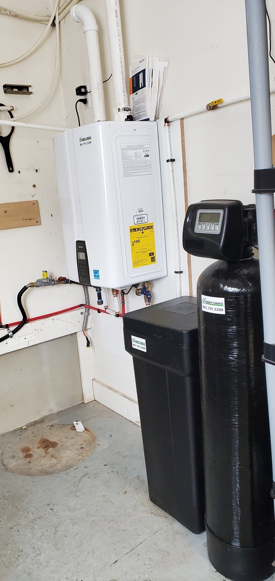 A water softener is sitting next to a water heater in a garage.