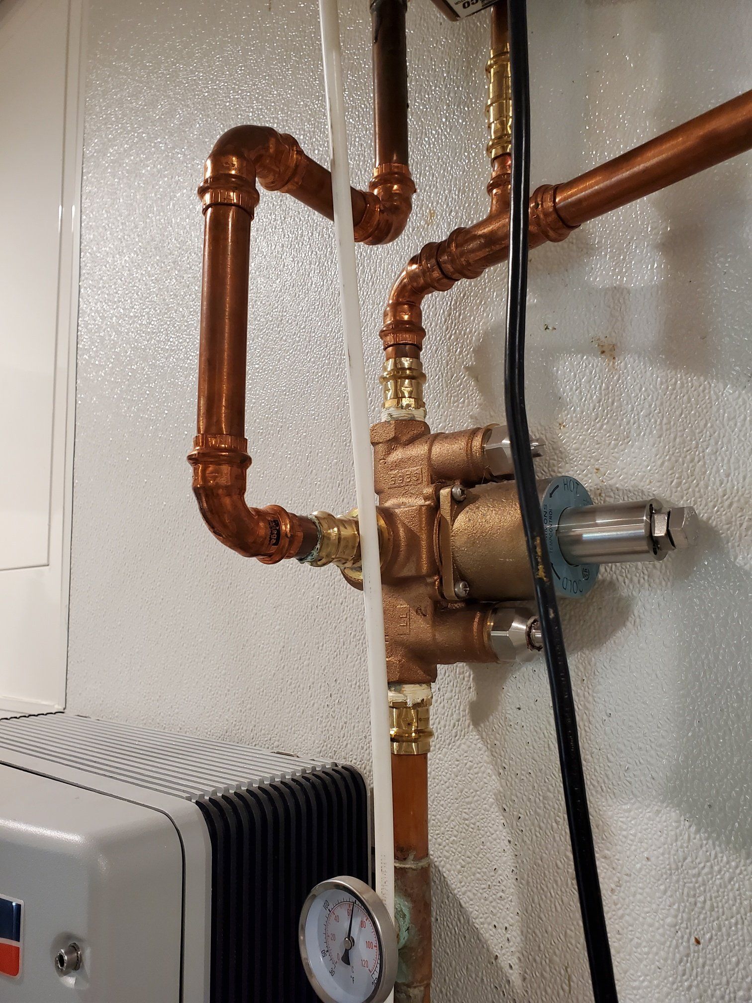 A close up of a copper pipe with a gauge attached to it.