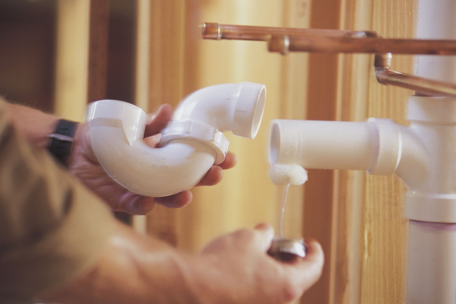 A plumber is fixing a pipe in a bathroom.