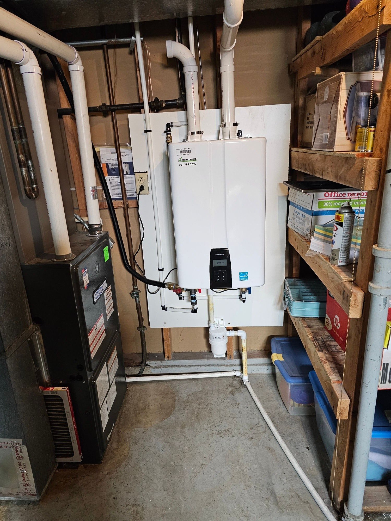 A boiler is sitting in a basement next to a furnace.