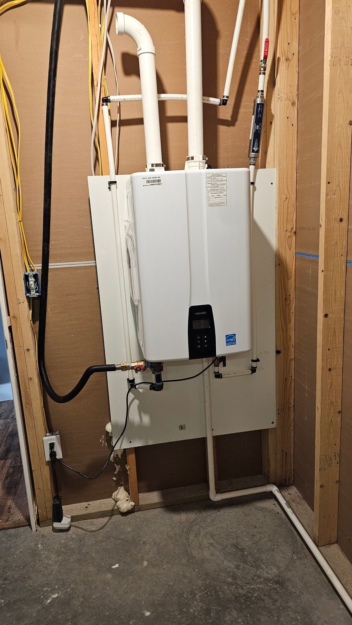 A white water heater is mounted to the wall in a room.