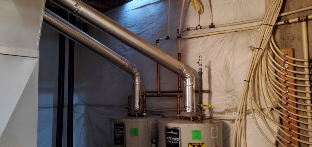 A couple of water heaters are sitting in a room next to each other.