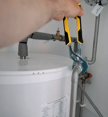 A person is fixing a water heater with a pair of pliers