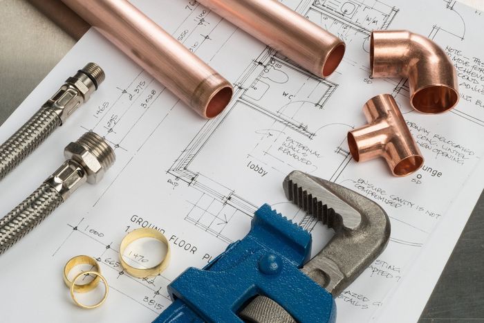 Copper pipes and a wrench on top of a blueprint
