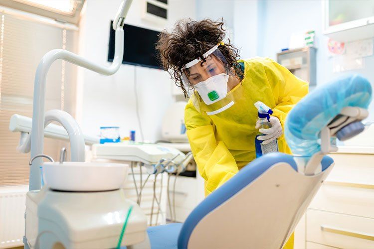 Dentist in yellow protective gear working on a patient in a dental clinic