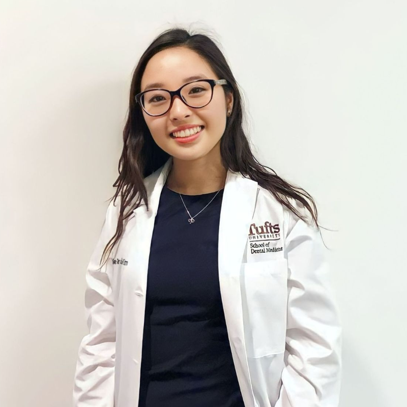 Smiling woman in a white coat standing in a bright hospital hallway