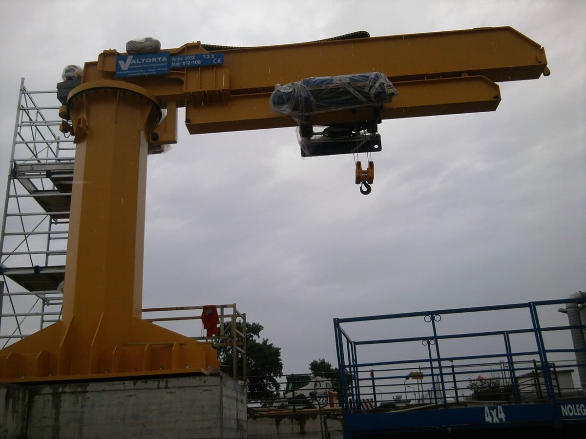 Gru a braccio industriale gialla contro un cielo nuvoloso.