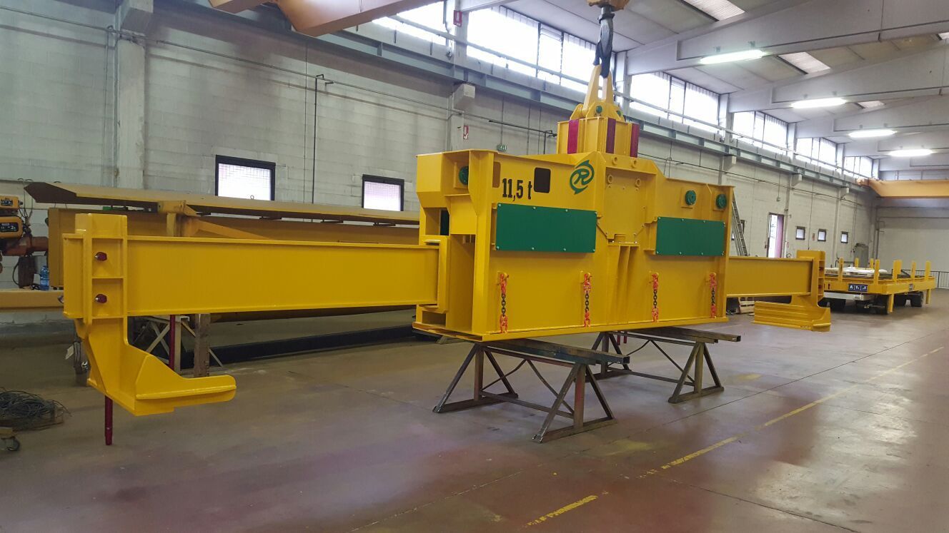 Componente giallo di un macchinario industriale in una fabbrica, sospeso da una gru.