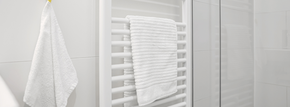 A white towel rack with two white towels hanging on it in a bathroom.