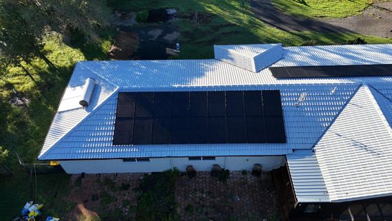 Solar water heater on a red tiled roof against a blue sky.