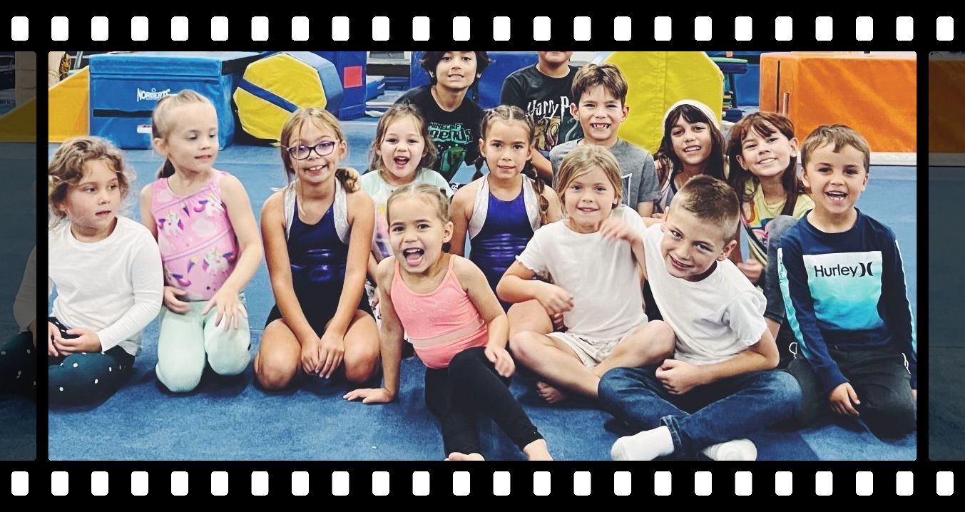 A group of children are posing for a picture while sitting on the floor.