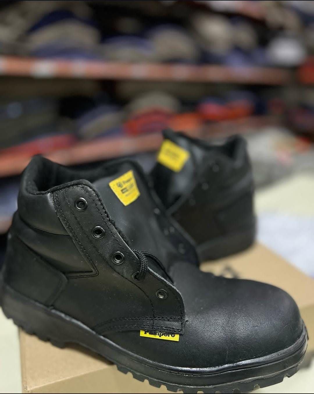 Botas de trabajo negras con etiquetas amarillas expuestas en un estante de una tienda.