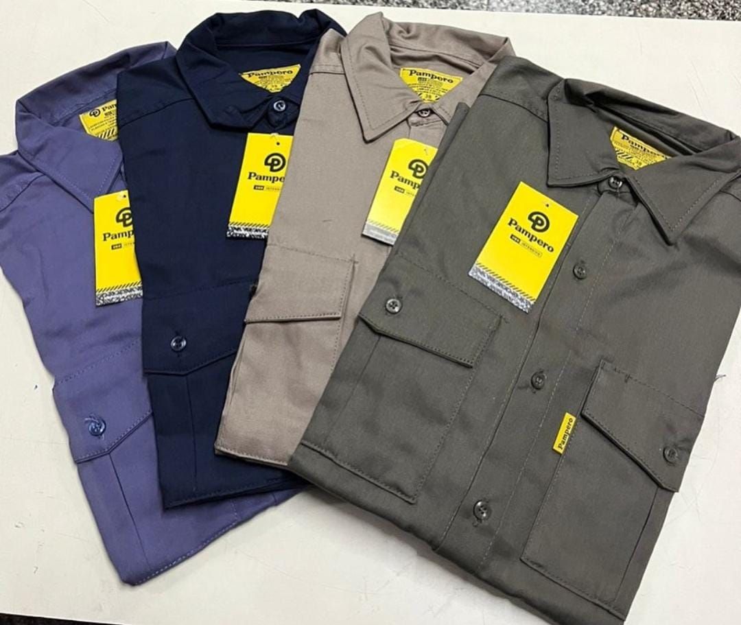 Cuatro camisas de trabajo dobladas con botones en azul marino, gris y caqui con etiquetas amarillas sobre fondo blanco.