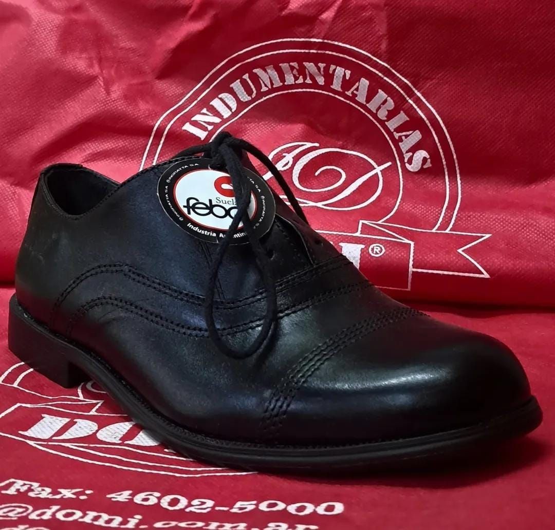 Zapato de vestir de cuero negro sobre fondo rojo con logotipo y texto blanco.