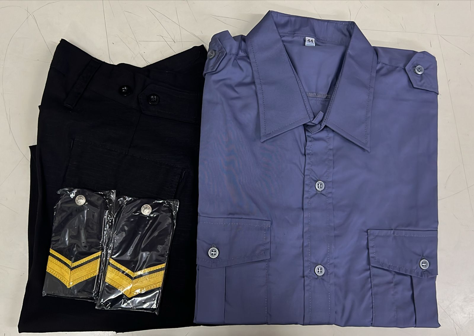 Dos camisas dobladas, una negra y otra azul, colocadas una al lado de la otra con los bolsillos estampados a la vista.