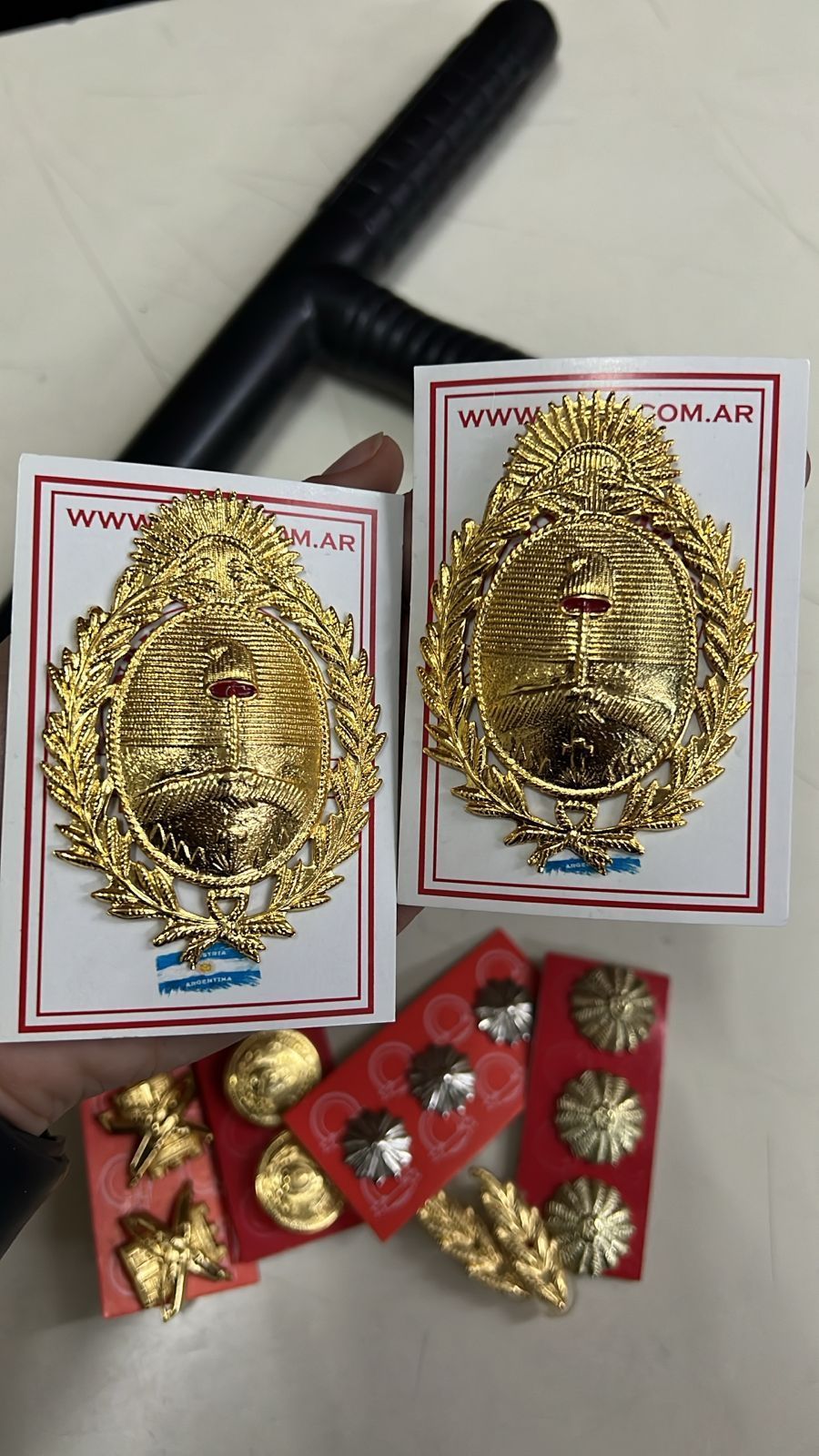 Insignias decorativas doradas sobre tarjetas blancas de presentación, con paquetes debajo adornados con detalles dorados y rojos.