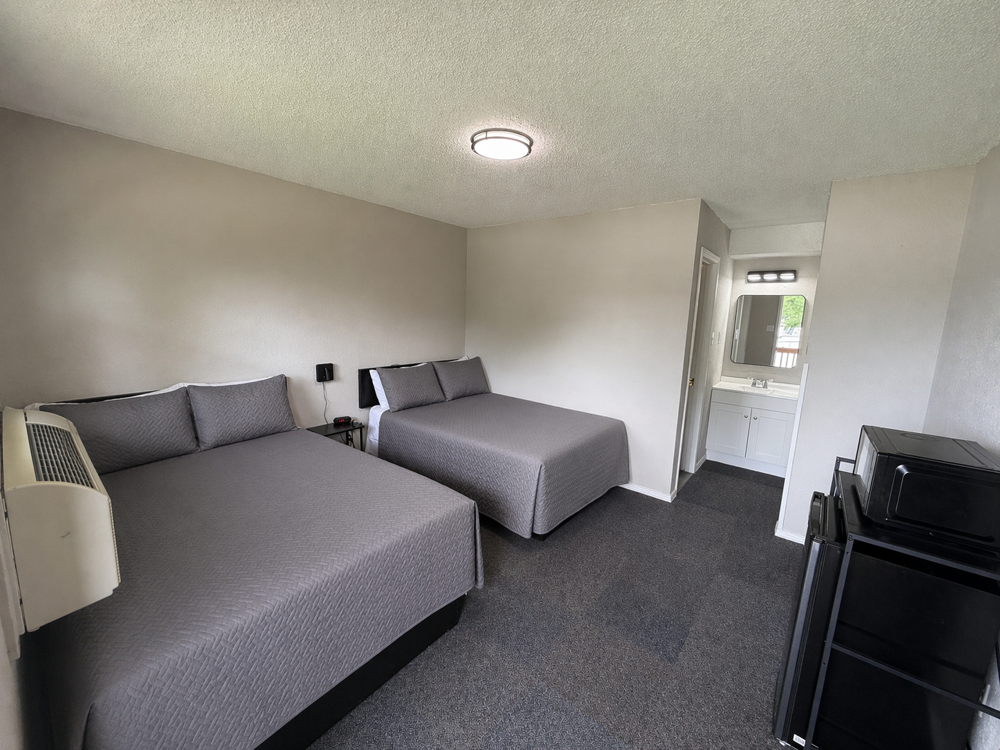 Small bedroom with two gray beds, a dresser, and a door leading outside.