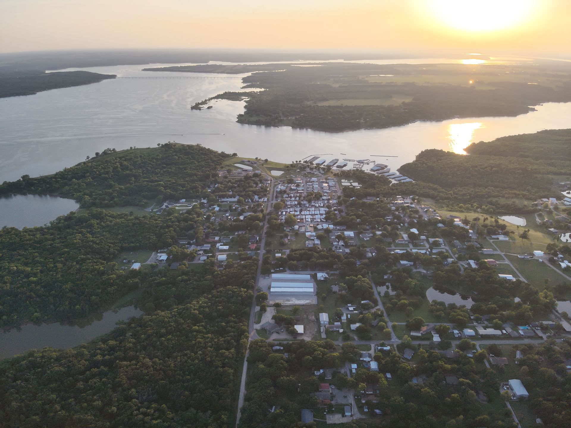 Aerial view of a coastal town at sunset, with water and islands surrounding the settlement.