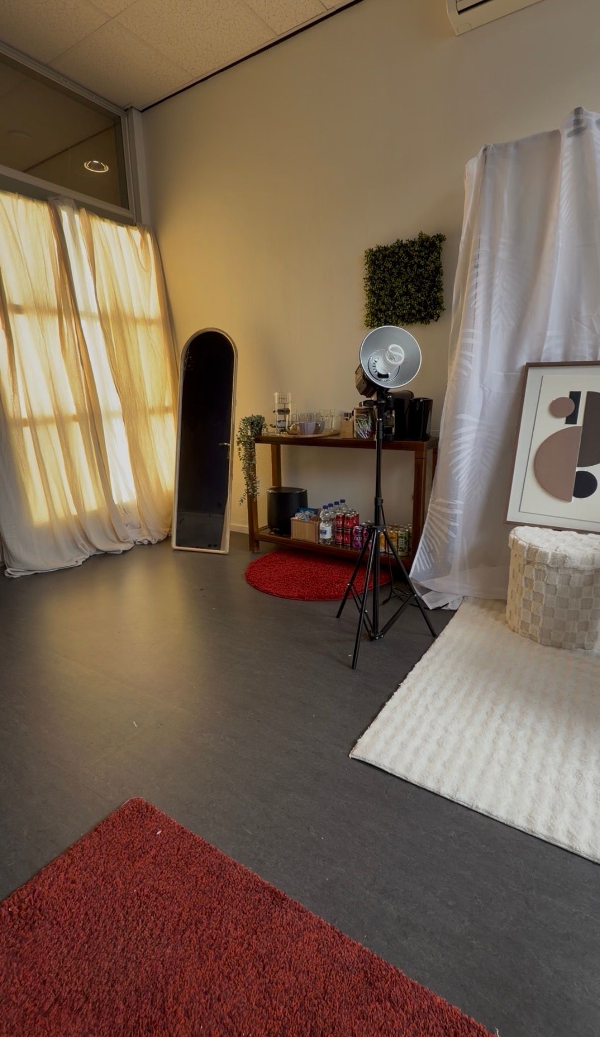 Kleine kamer met een kaptafel, spiegel, gordijnen, vloerkleed en een zwarte staande kast tegen de muur.