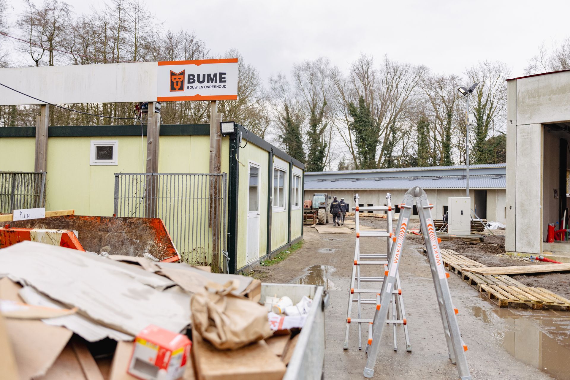 Bouwterrein met modulaire gebouwen en een bord met de tekst 