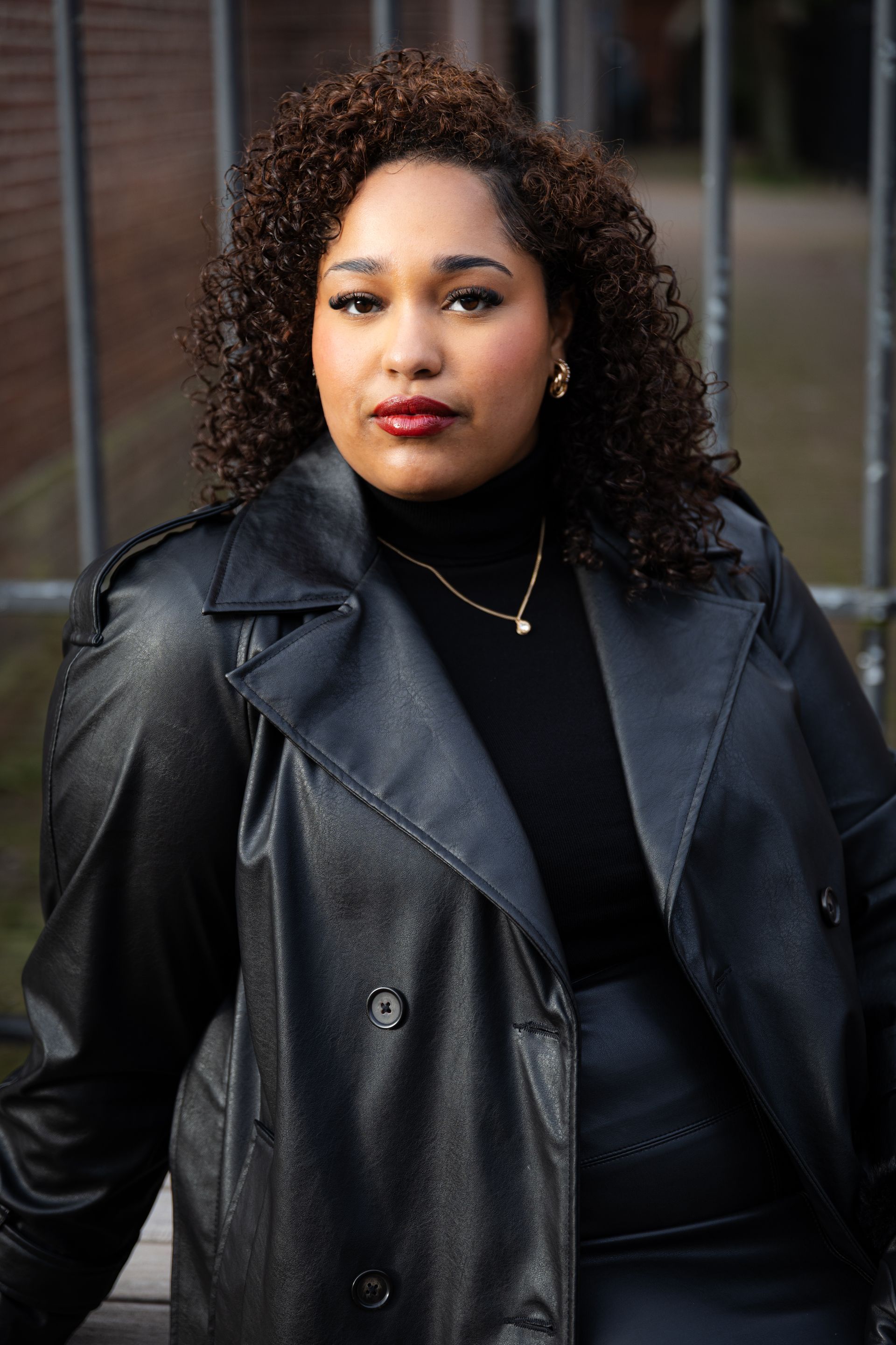 Vrouw in zwarte leren jas en coltrui, kijkt in de camera.