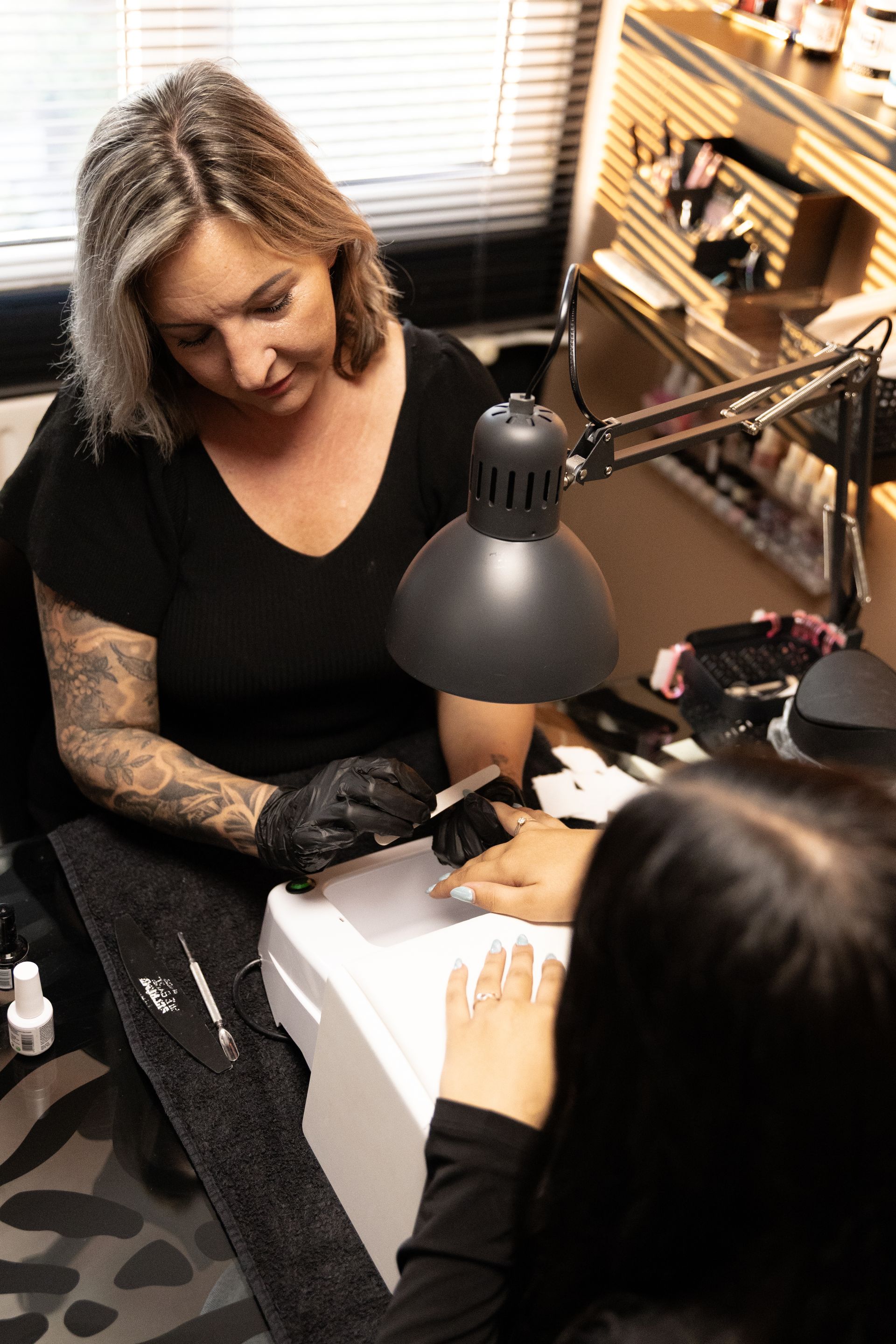 Een vrouw brengt nagellak aan op de hand van een andere klant in een nagelsalon.