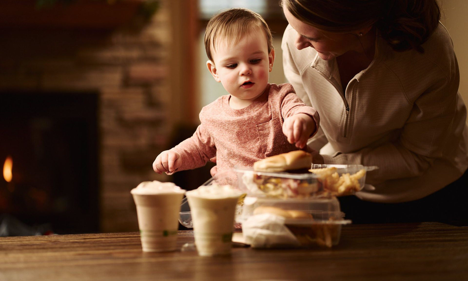 Baby reaching for corn plastic (PLA) containers on table with food