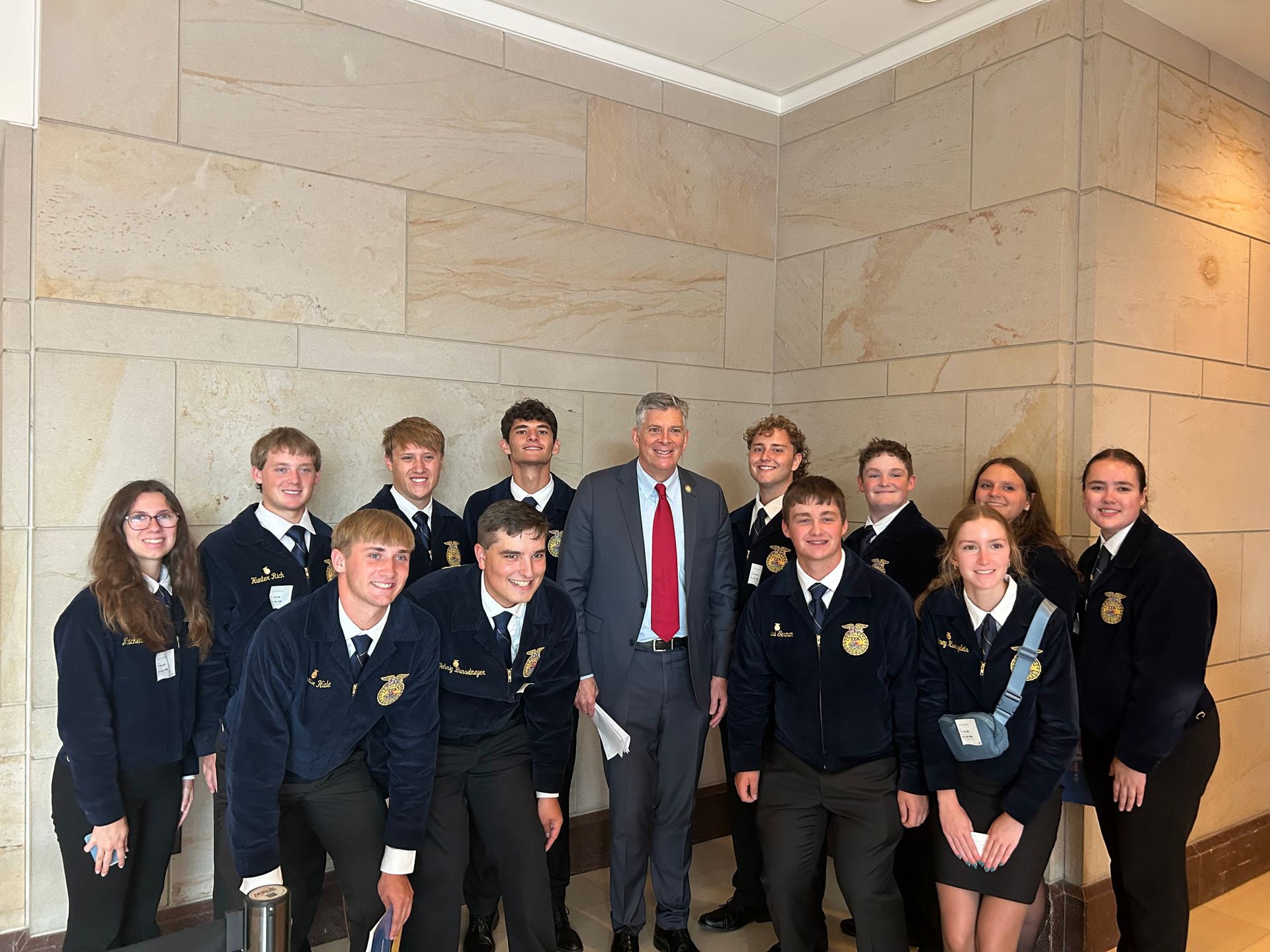 Group of FFA members with a man in a suit, in a hallway.