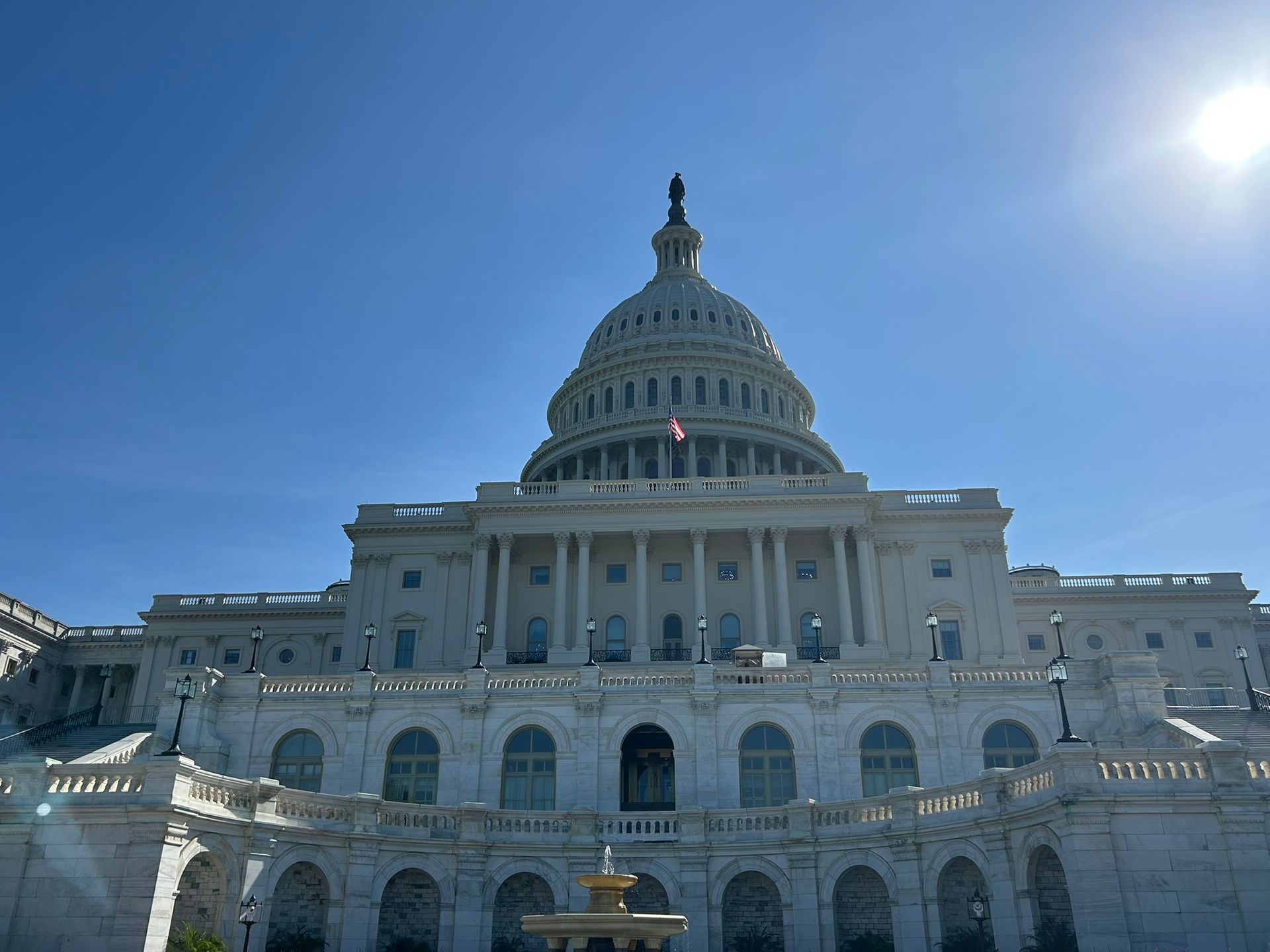 U.S. Capitol building under a clear blue sky with bright sunlight