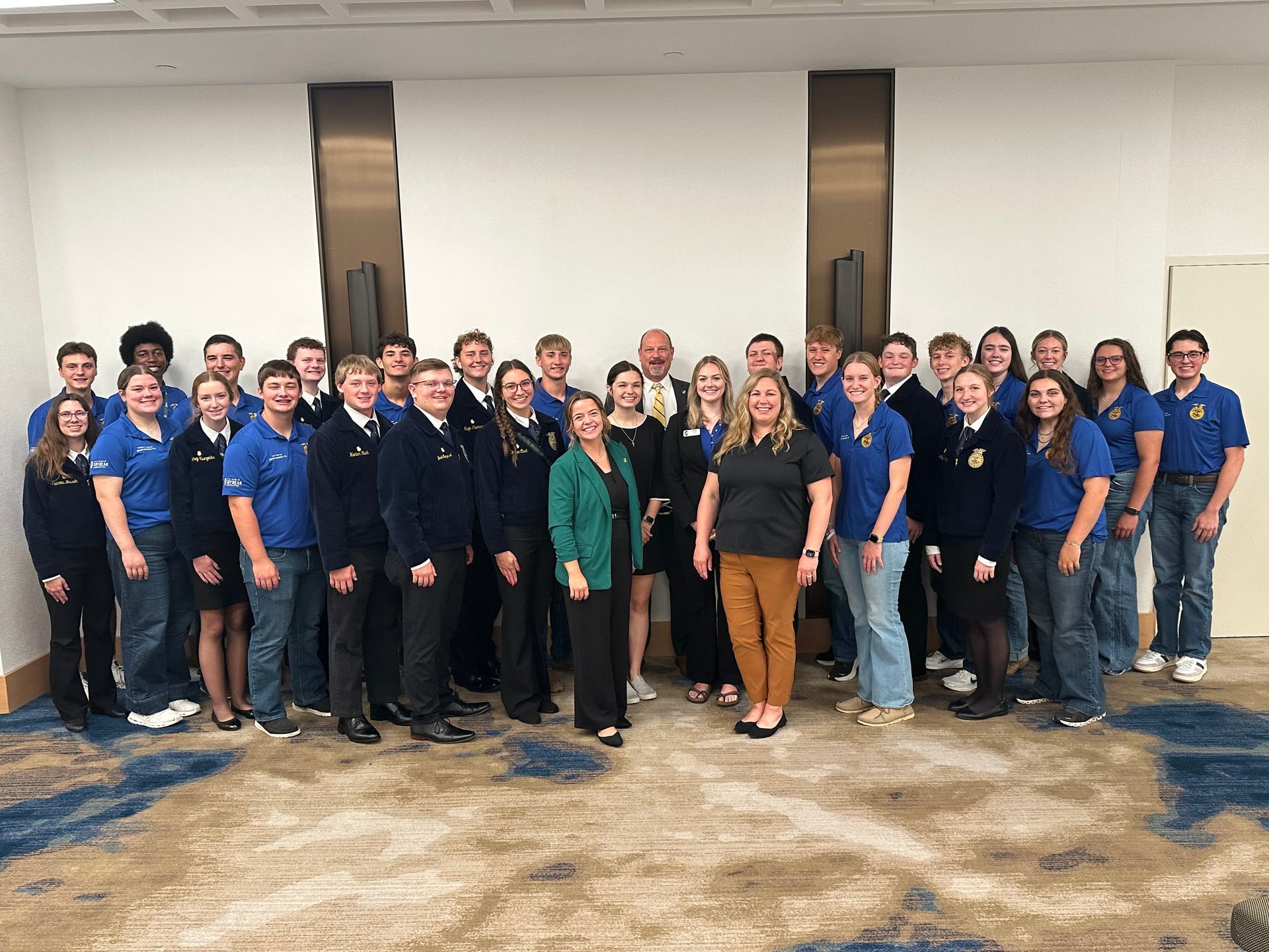 Group of people, including FFA members, posing for a photo indoors.