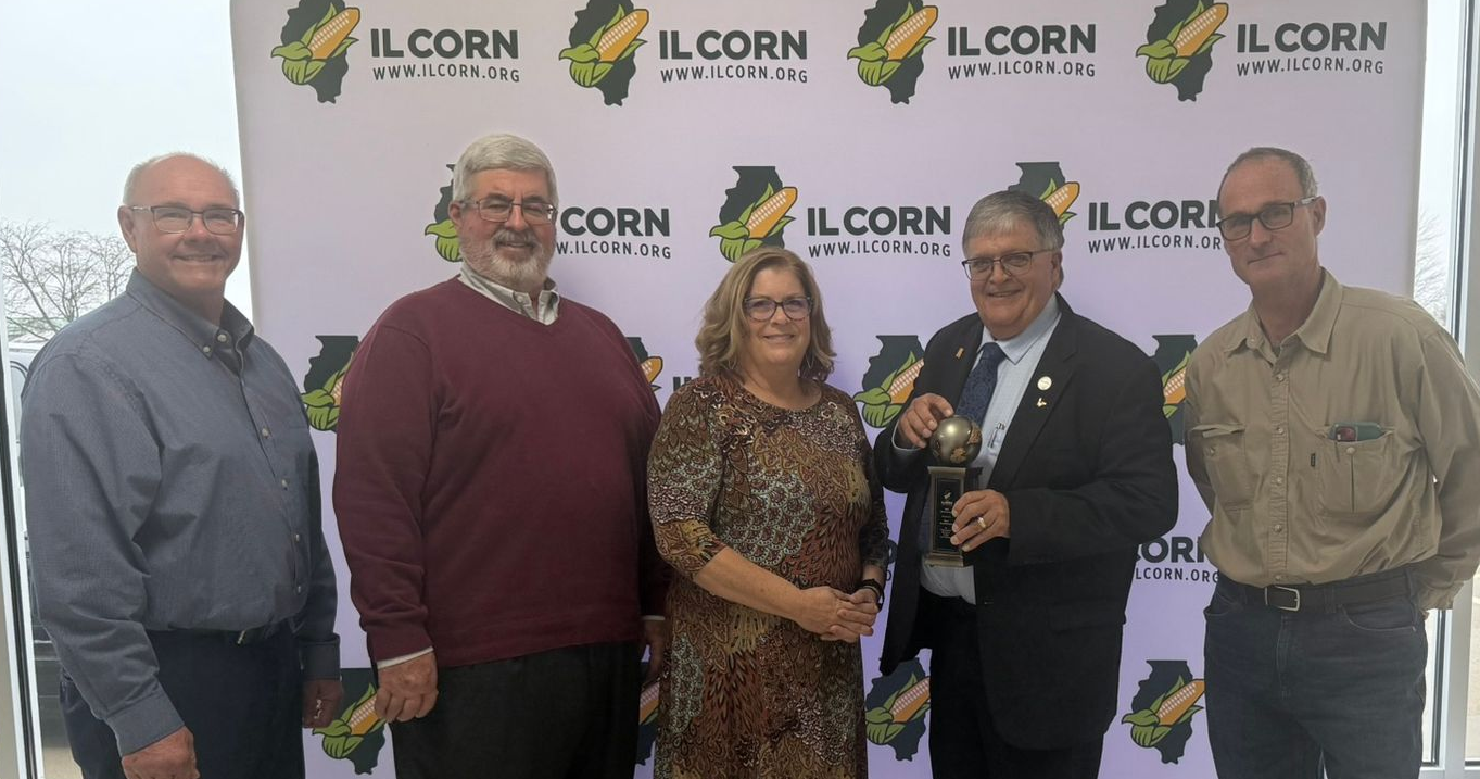 Five people pose with an award in front of an IL Corn backdrop.