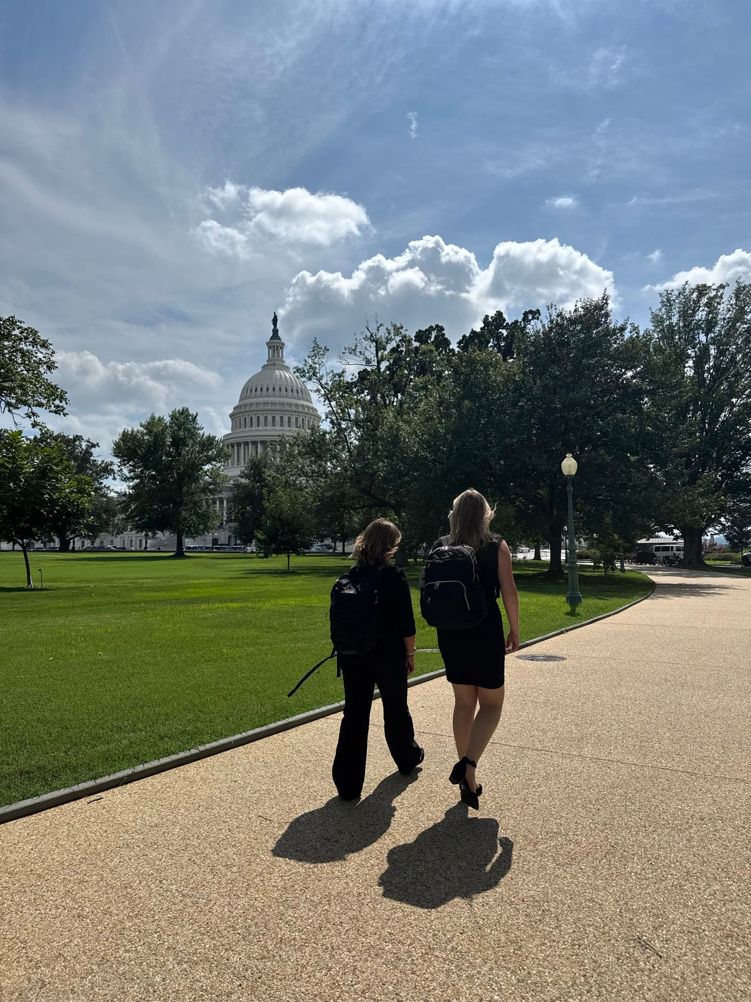 Two people walk toward the U.S. Capitol Building on a sunny day.