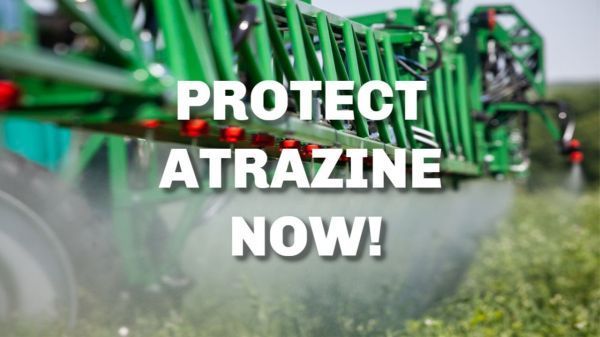 A green tractor spraying a field with the words `` protect atrazine now ''.