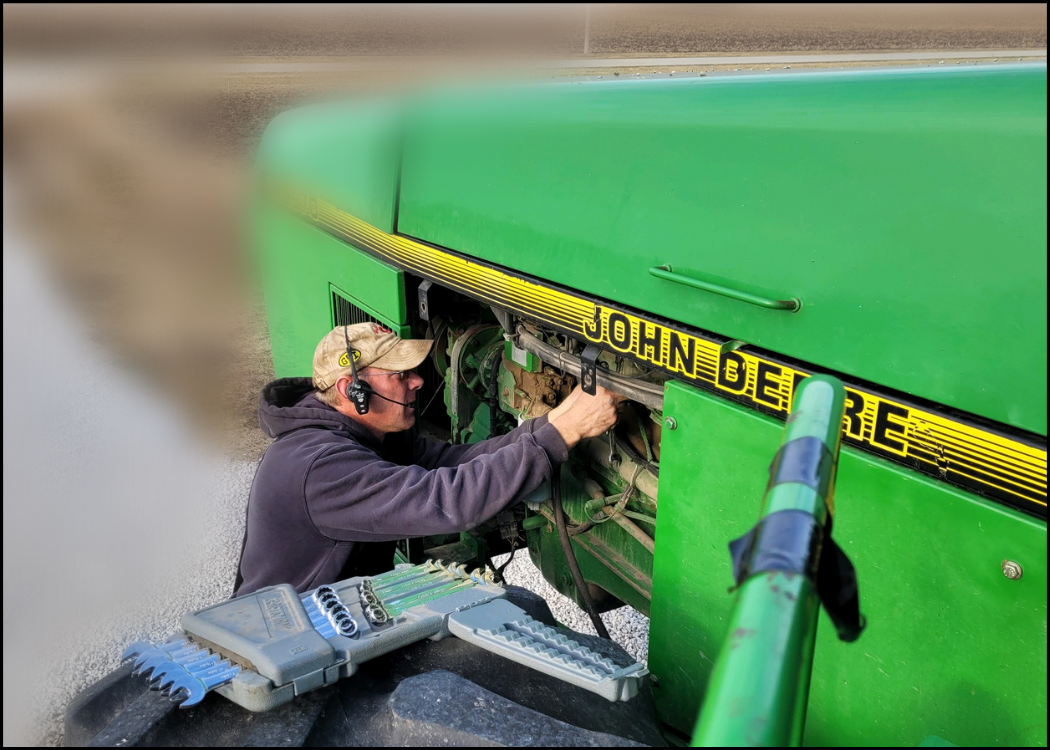 farmer next to engine with headphones on