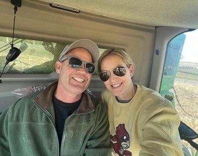 A man and a woman are posing for a picture in the back of a truck.