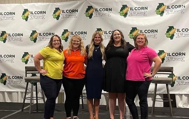 Five women posing at an event with