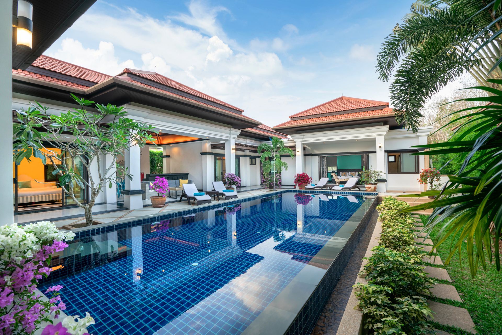 Courtyard villa with a blue tiled pool, lounge chairs, and tropical plants