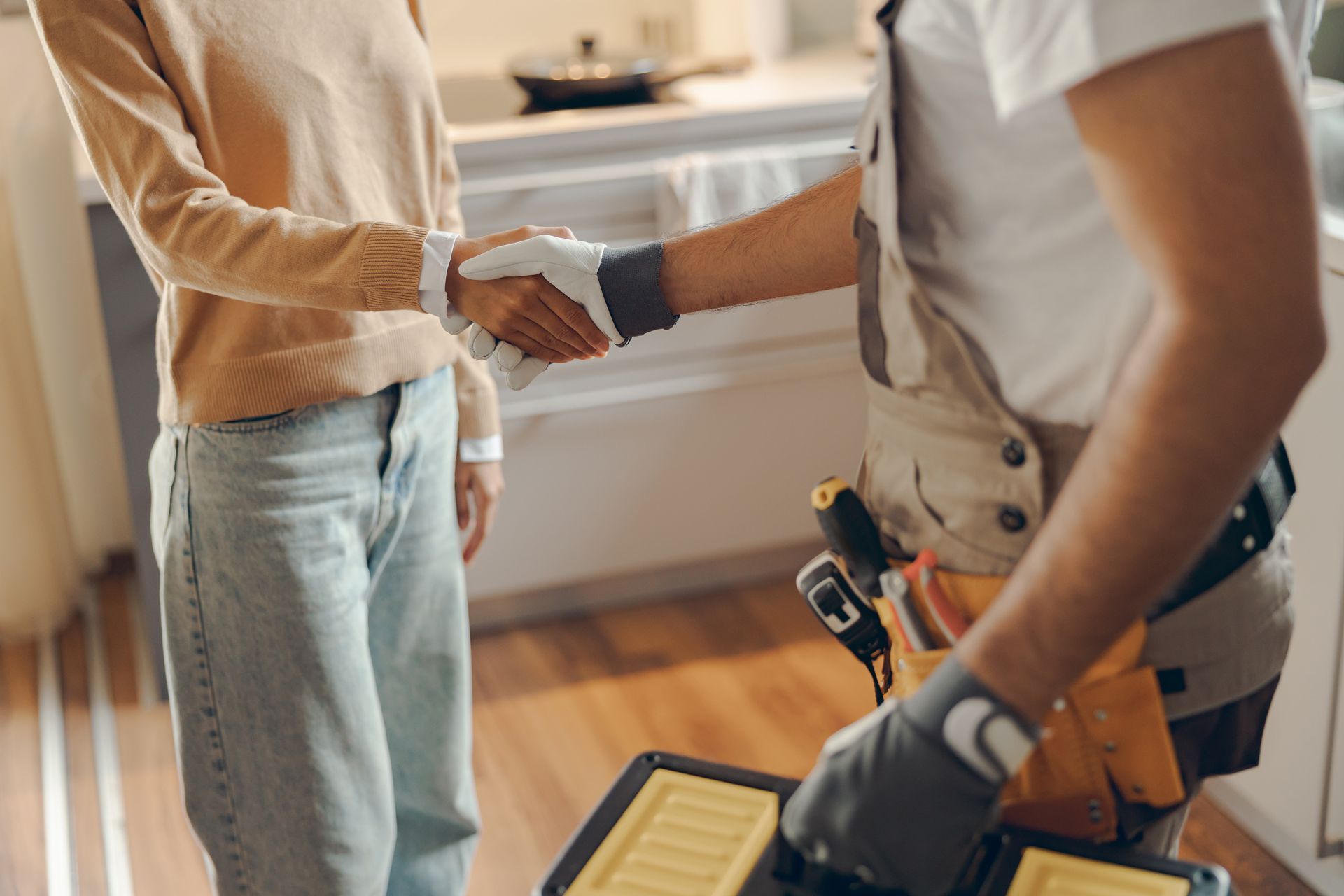 Close-up of a repairman in uniform shaking hands with a woman. Close-up of a repairman in uniform shaking hands with a woman.