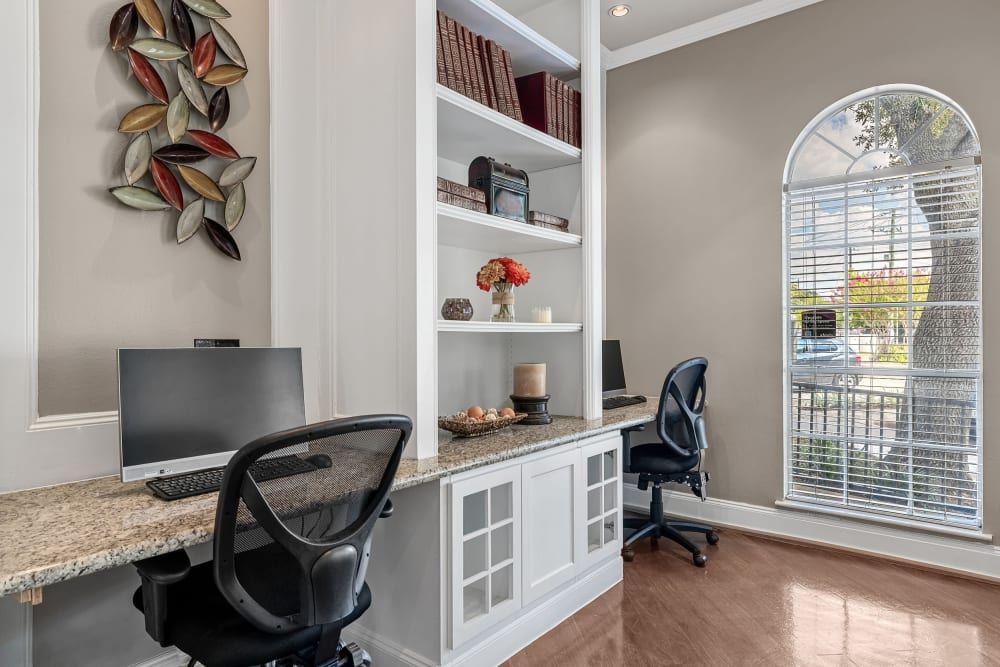 a room with two desks, two chairs, a computer, and a window at Marquis on Westheimer in Houston, TX.