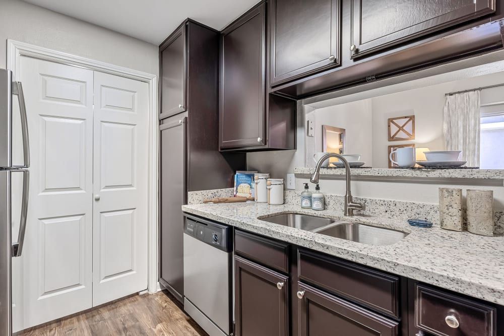 a kitchen with stainless steel appliances, granite counter tops, and brown cabinets at Marquis on Westheimer in Houston, TX.