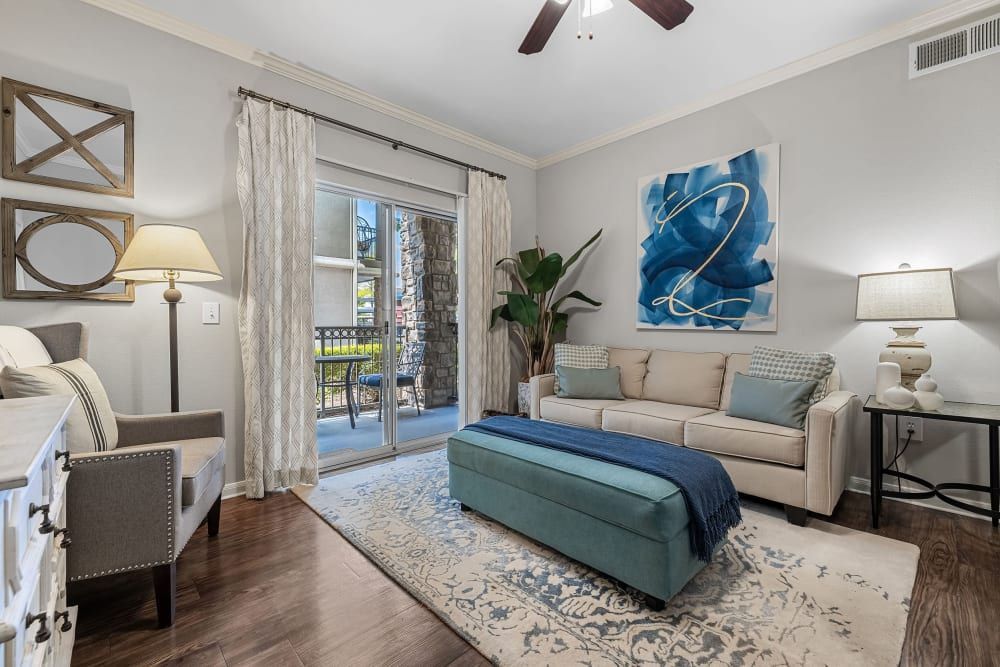a living room with a couch, chair, ottoman, and a ceiling fan at Marquis on Westheimer in Houston, TX.