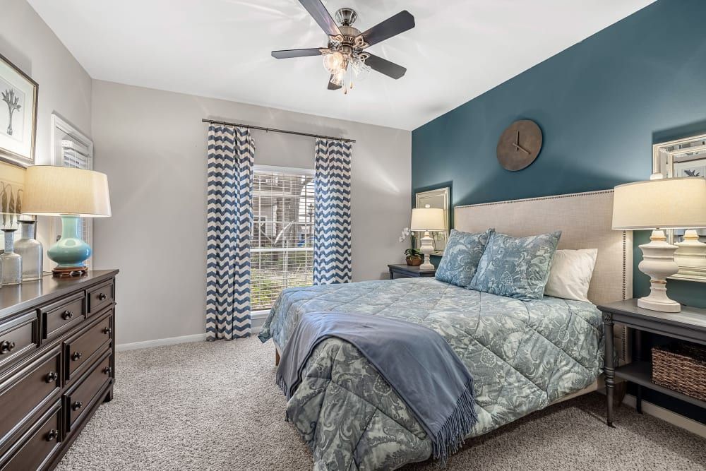 a bedroom with a bed, dresser, lamps, and a ceiling fan at Marquis on Westheimer in Houston, TX.
