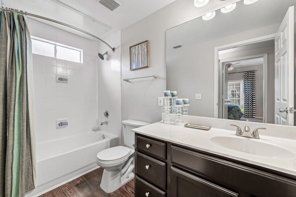 a bathroom with a toilet, sink, bathtub, and mirror at Marquis on Westheimer in Houston, TX.