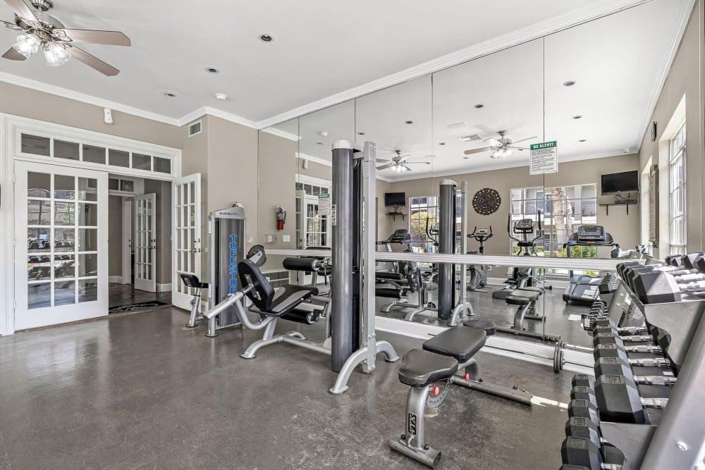 a large gym with a lot of exercise equipment and a ceiling fan at Marquis on Westheimer in Houston, TX.