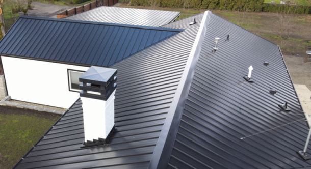 Aerial view of a gray metal-roofed house with a chimney and another building beside it