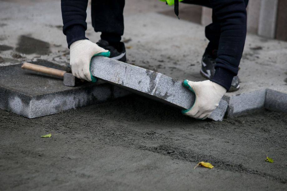 A person is laying bricks on a sidewalk.