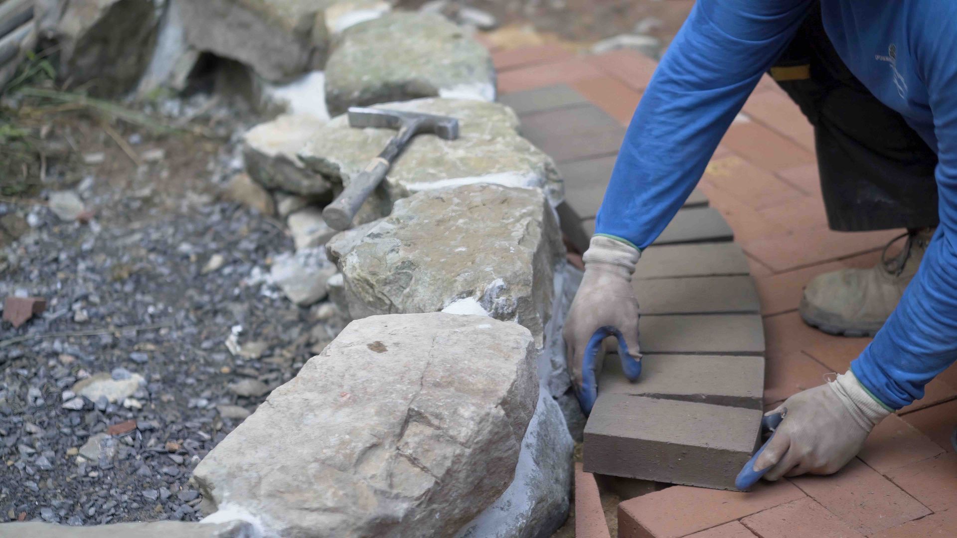 A man is laying bricks on a brick walkway.