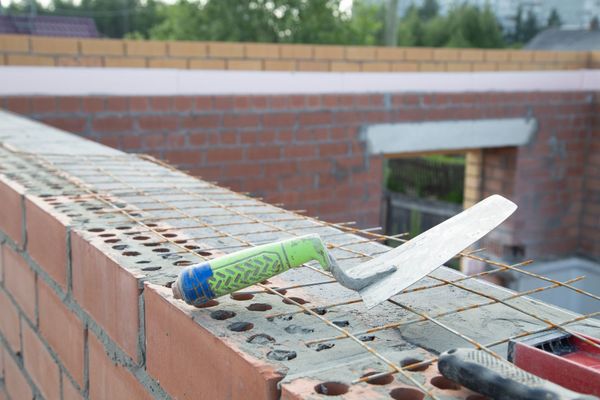 A trowel is laying on top of a brick wall.