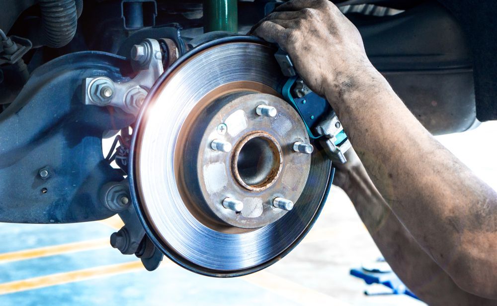 Mechanic Replacing Car Brake Disc. Hands Are Visible — Erina Mechanical Repairs In Erina, NSW