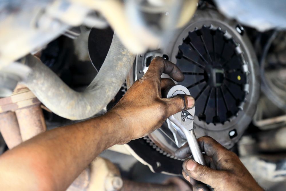 Mechanic's Hands, Covered in Grease, Working on A Car Clutch with A Wrench — Erina Mechanical Repairs In Erina, NSW